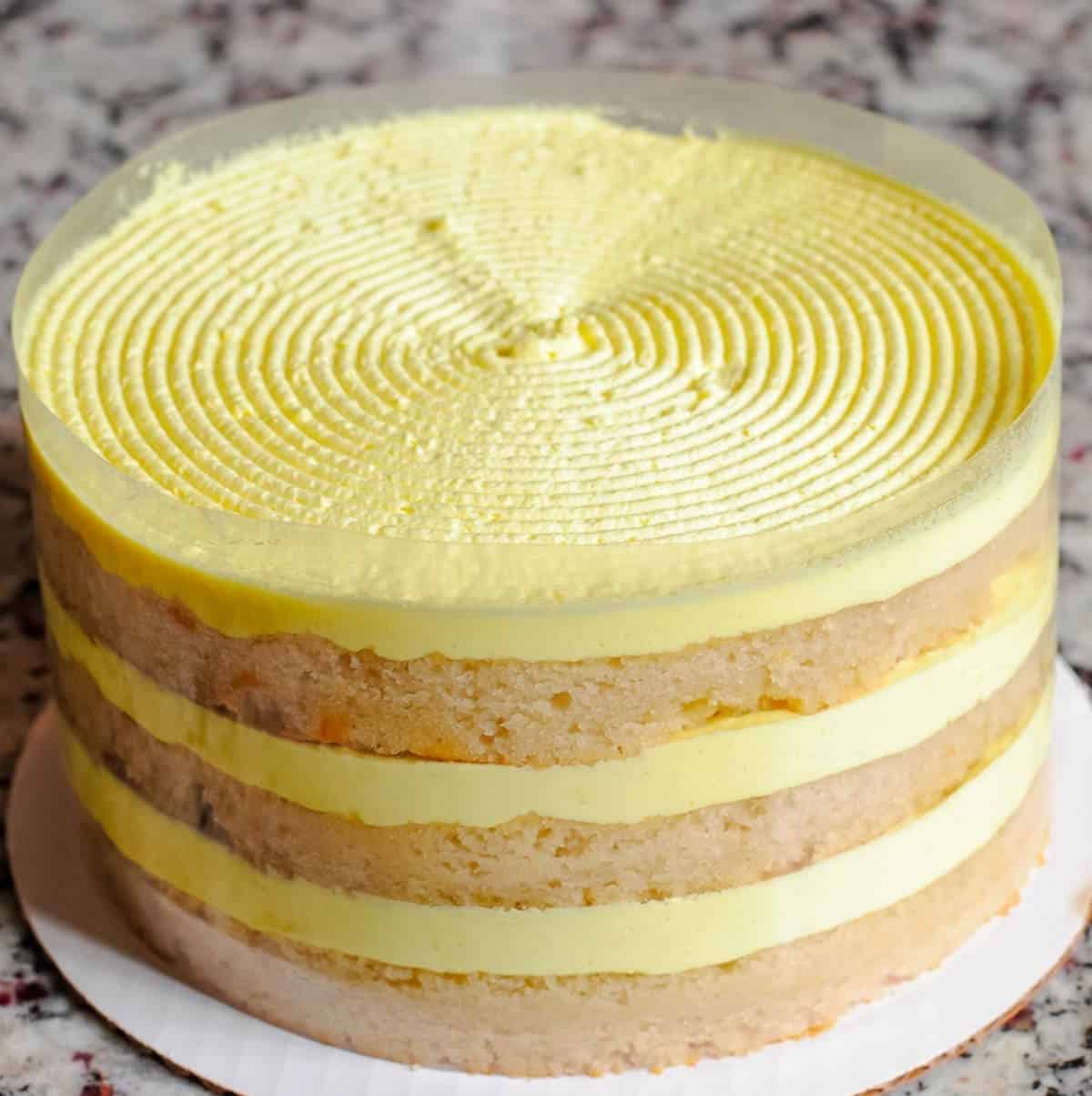 Three layer vegan lemon cake with yellow frosting between layers and on top.