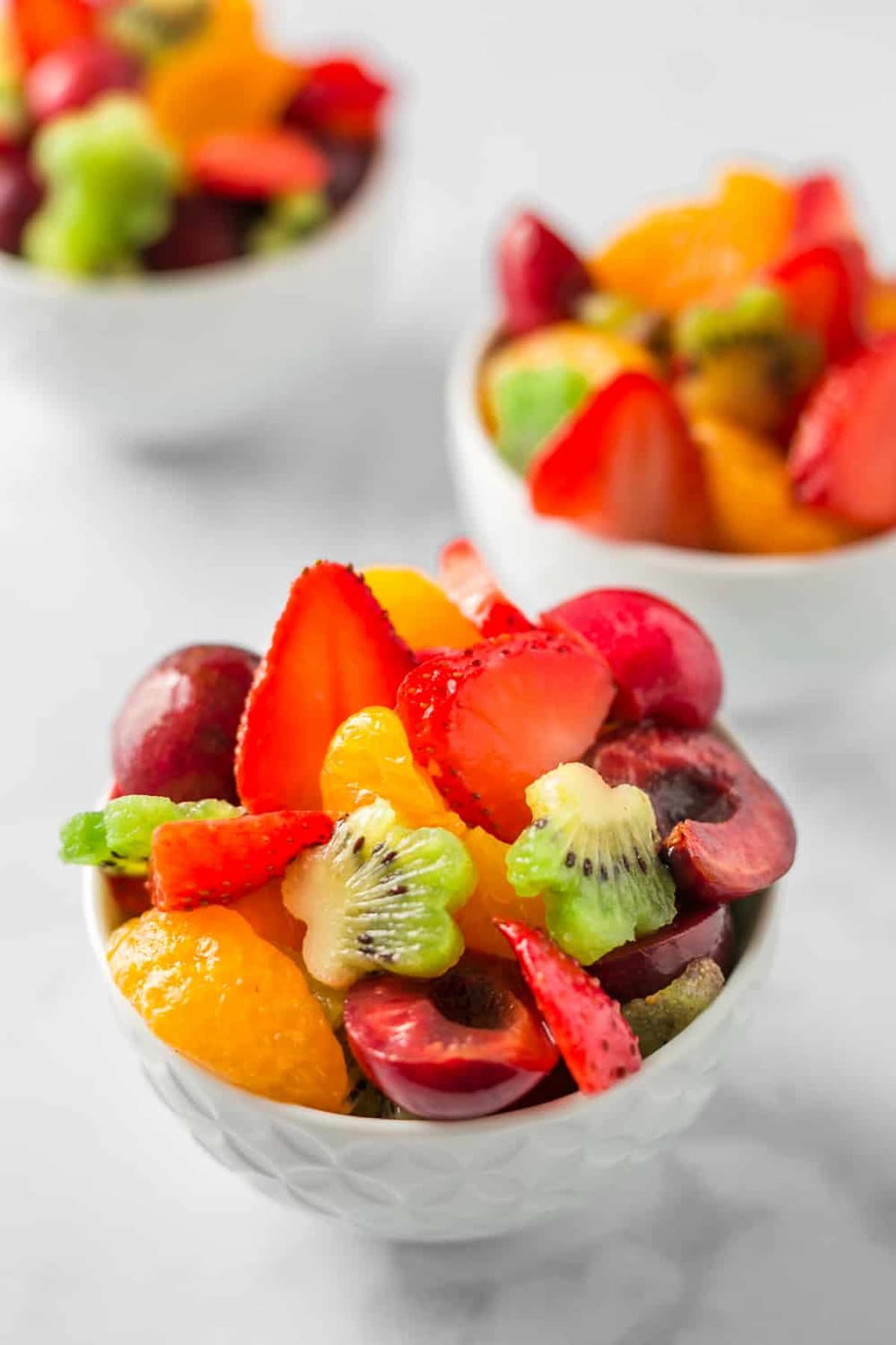 A bowl of colorful fruit salad cut into different shapes.