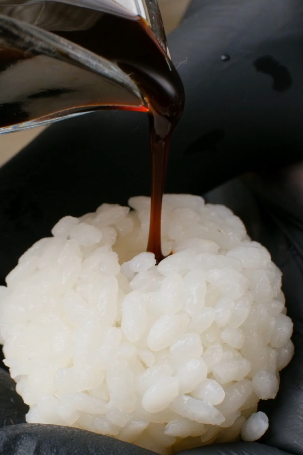 Hoisin sauce being poured into a rice ball.