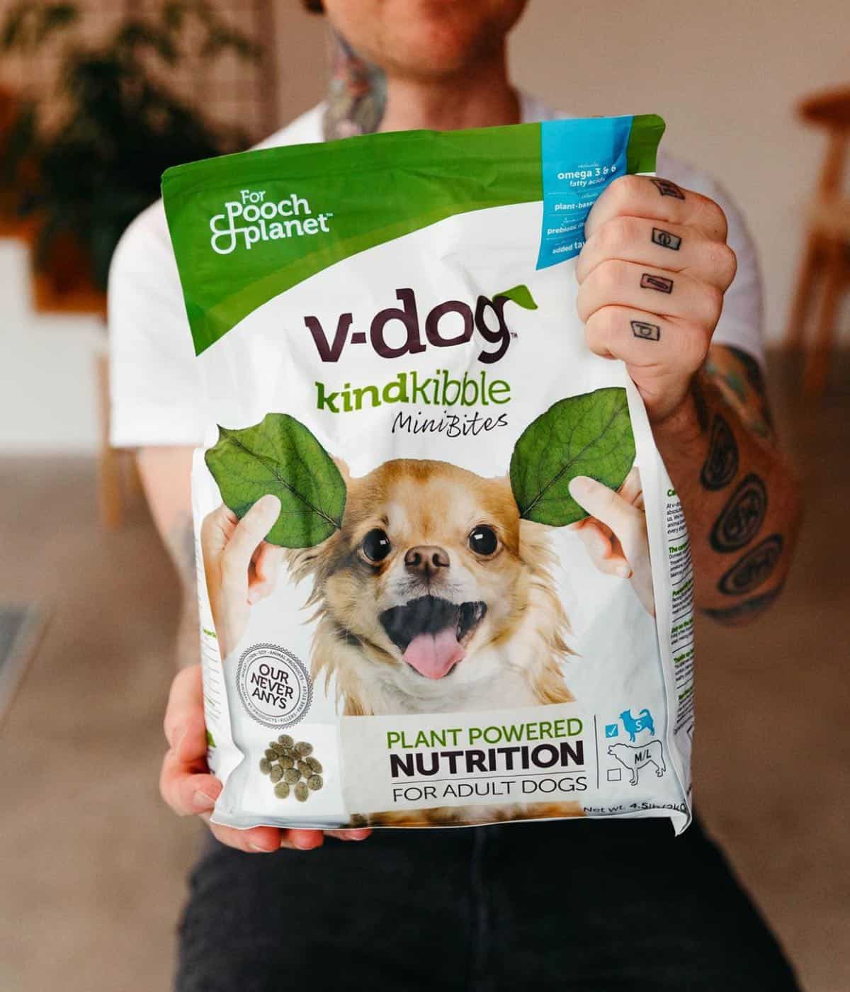 Vegan holding up a bag of V-Dog kinder kibble dog food. 