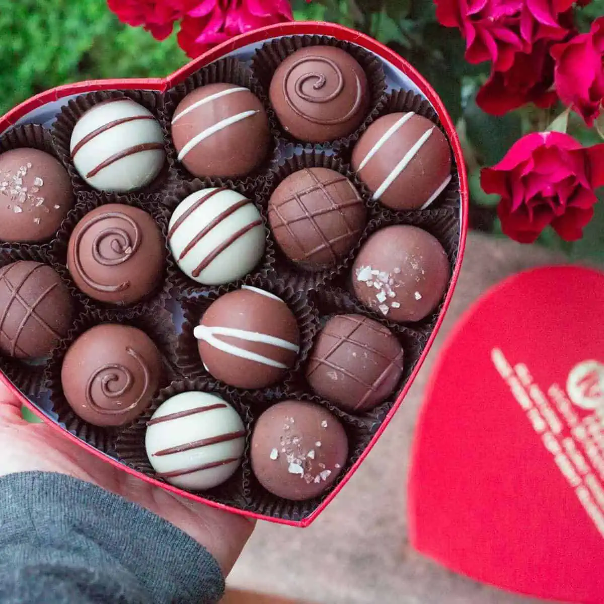 Heart shaped box of vegan chocolate truffles with white chocolate, dark chocolate, and plant based milk chocolate.
