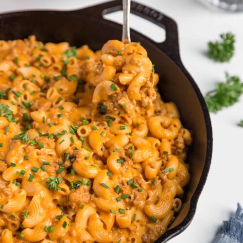 vegan hamburger helper in iron skillet with fork scooping pasta