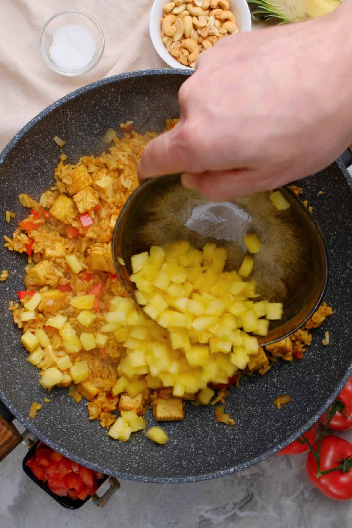 Pineapple being added to a skillet.