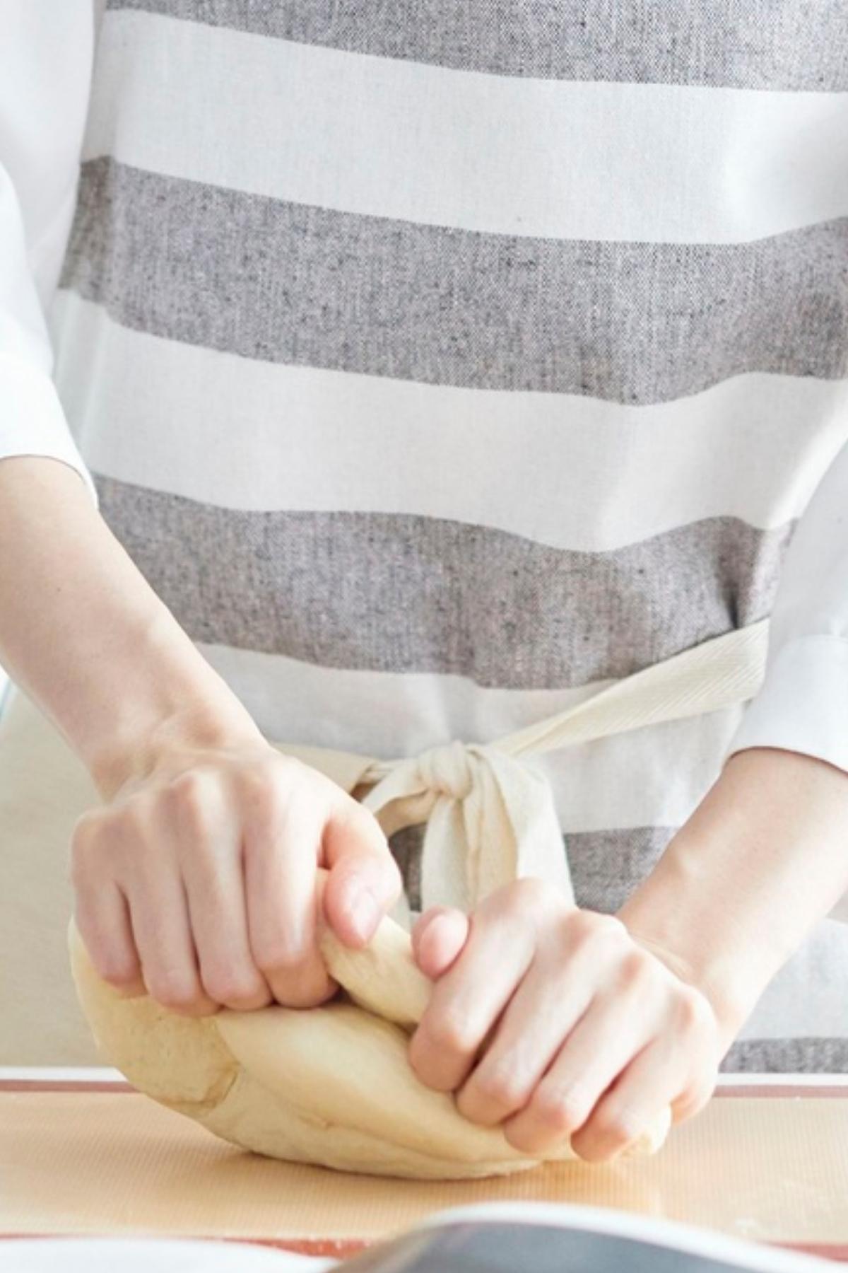Woman kneading pita dough.
