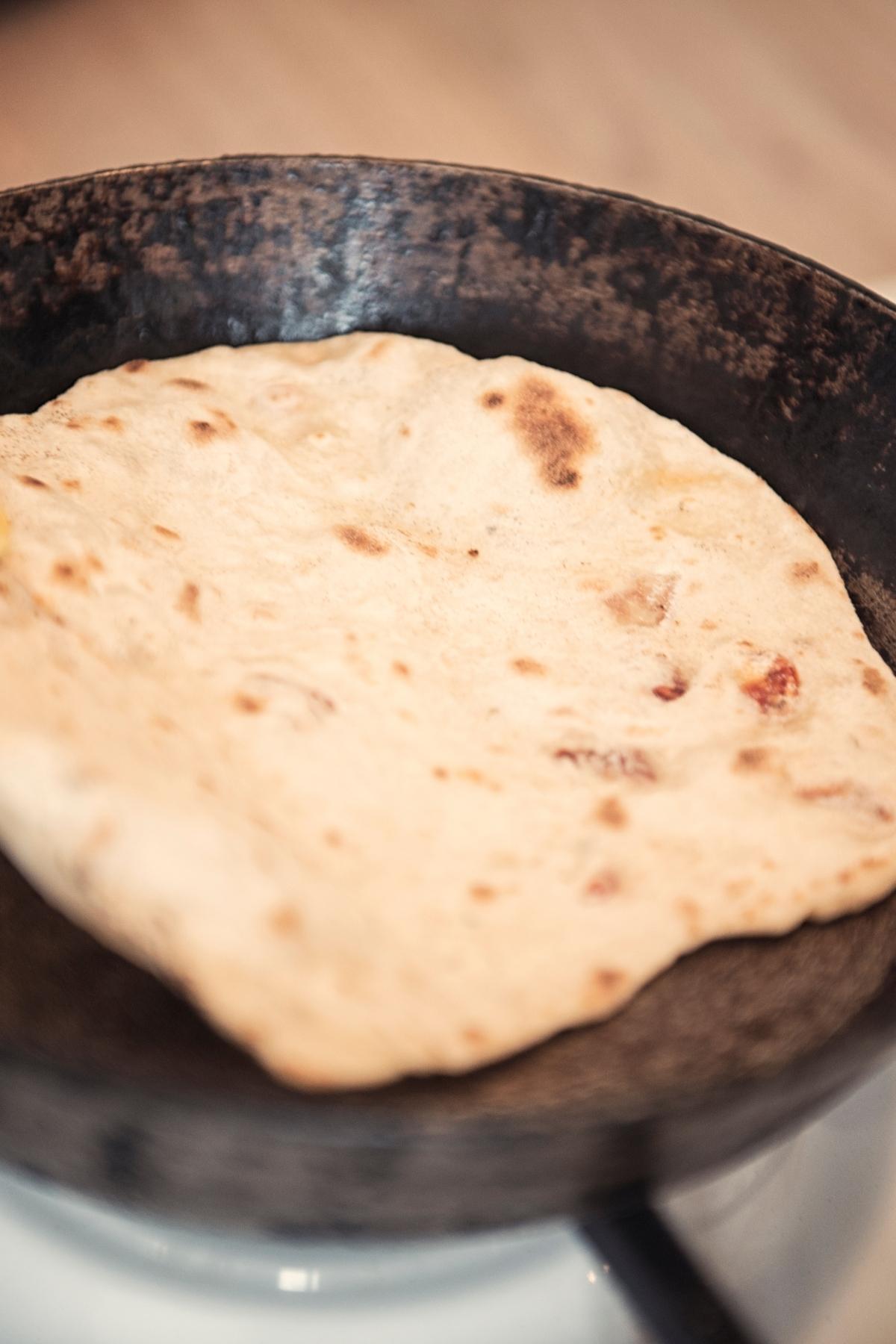 Homemade vegan pita being made in a hot skillet.