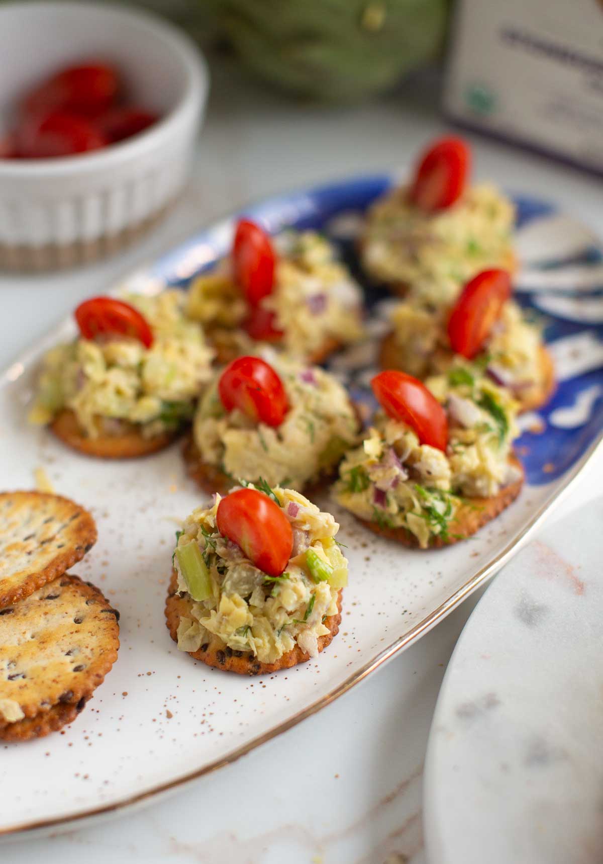 Vegan tuna salad appetizer on crackers with a cherry tomato