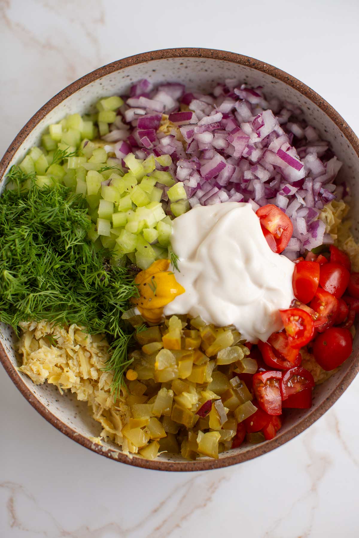 Artichoke tuna salad ingredients assembled in a bowl before mixing. 