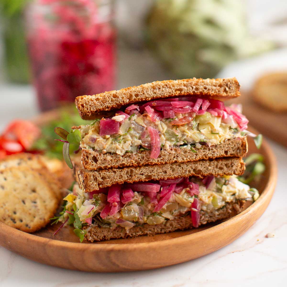 Artichoke tuna salad on a sandwich layered with pickled red onion.