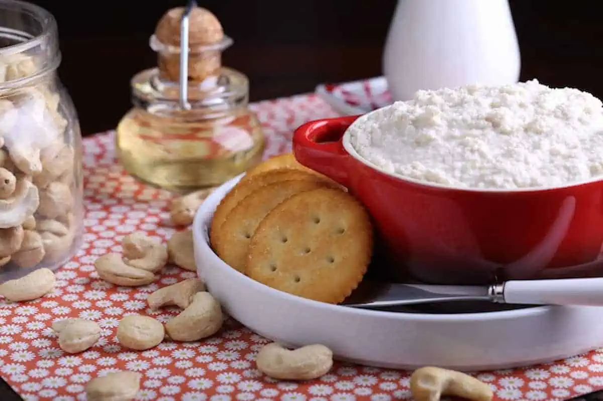 Cultured cashew vegan cheese in a bowl next to crackers and cashews.