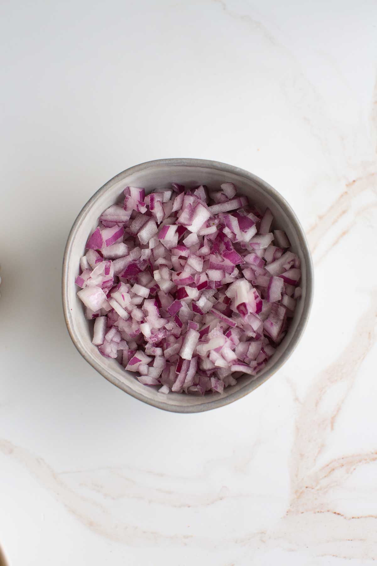 Finely diced red onion in a bowl. 