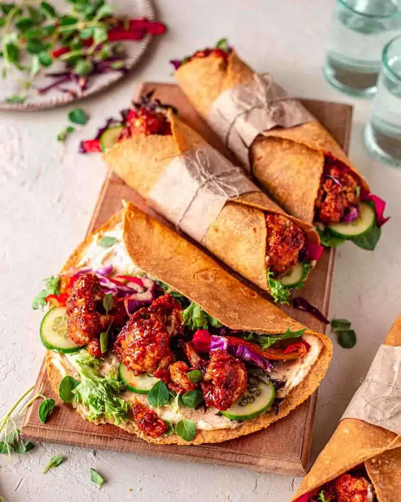 vegan wraps with maple bbq cauliflower, greens, cucumber, bell peppers, and a butter bean spread on a tortilla