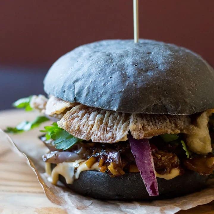 Up close of black burger with oyster mushrooms and spicy eggplant.