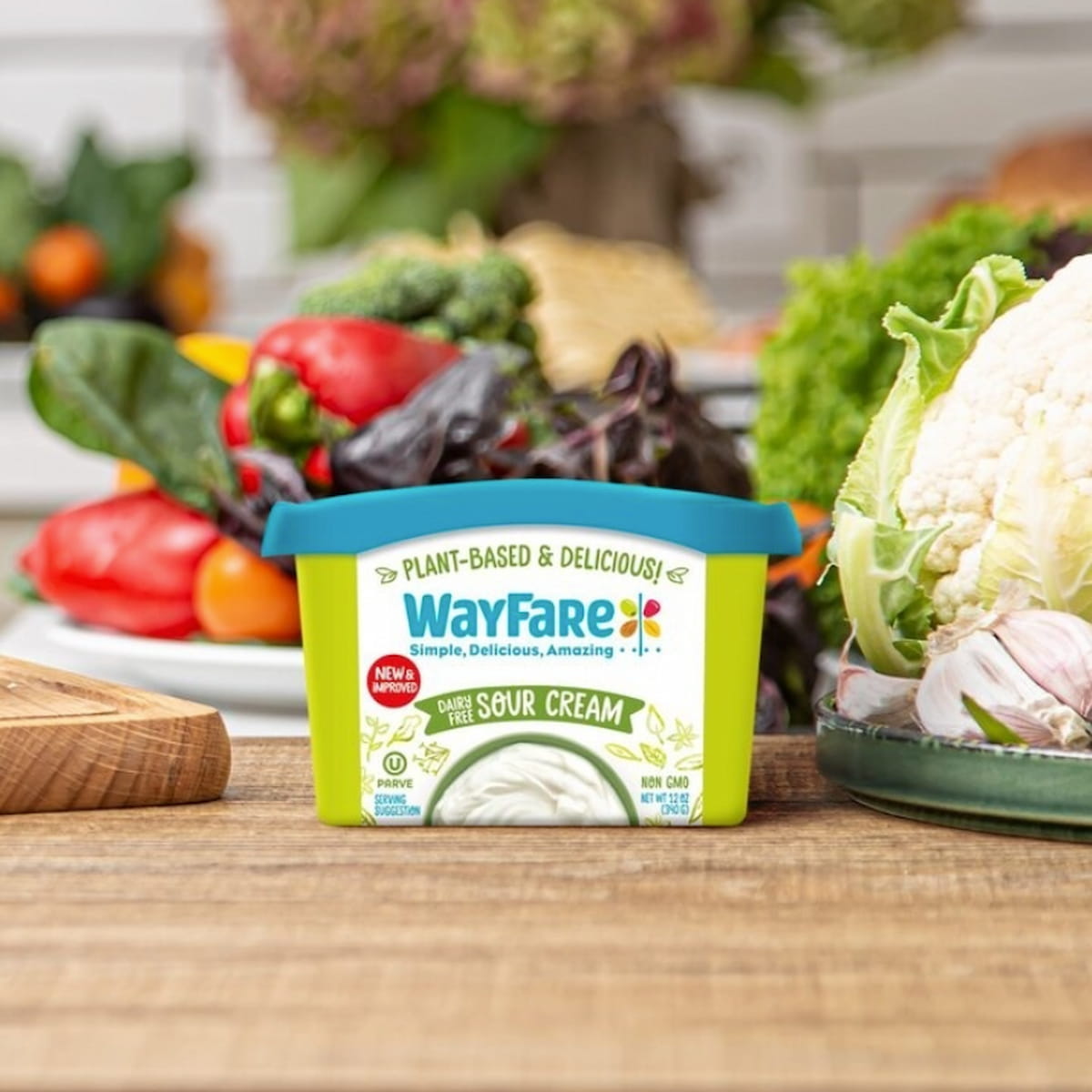 Container of Wayfare dairy-free sour cream with fresh veggies in the background.