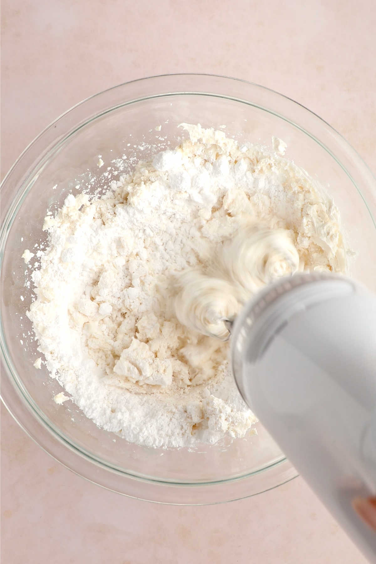 Vegan frosting being whipped with a hand mixer during the creaming stage.