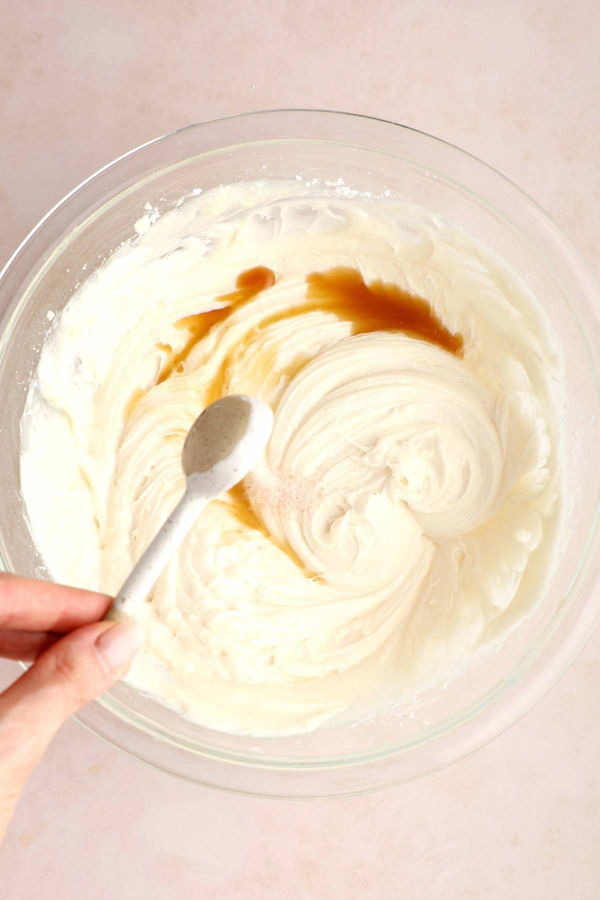 Adding vanilla extract to vegan cream cheese frosting.