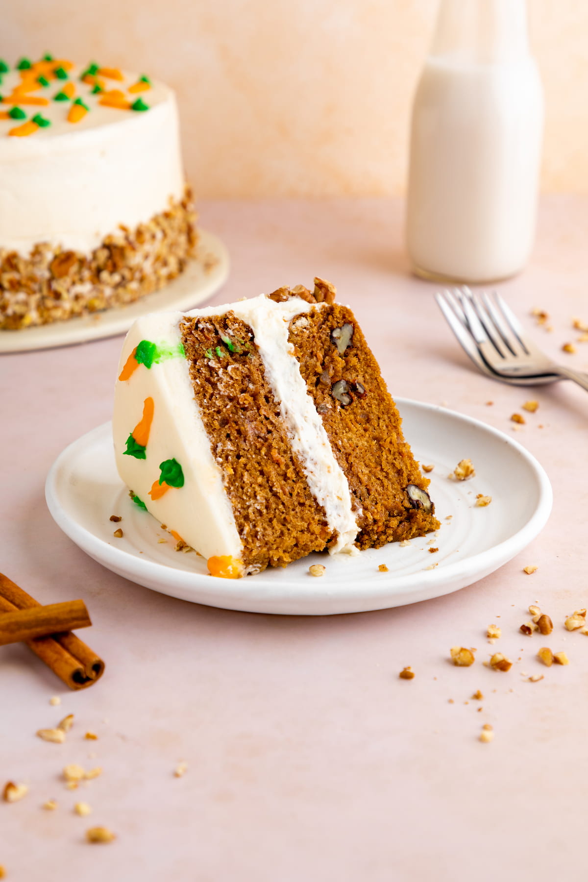 Slice of vegan carrot cake topped with tangy plant-based cream cheese frosting.