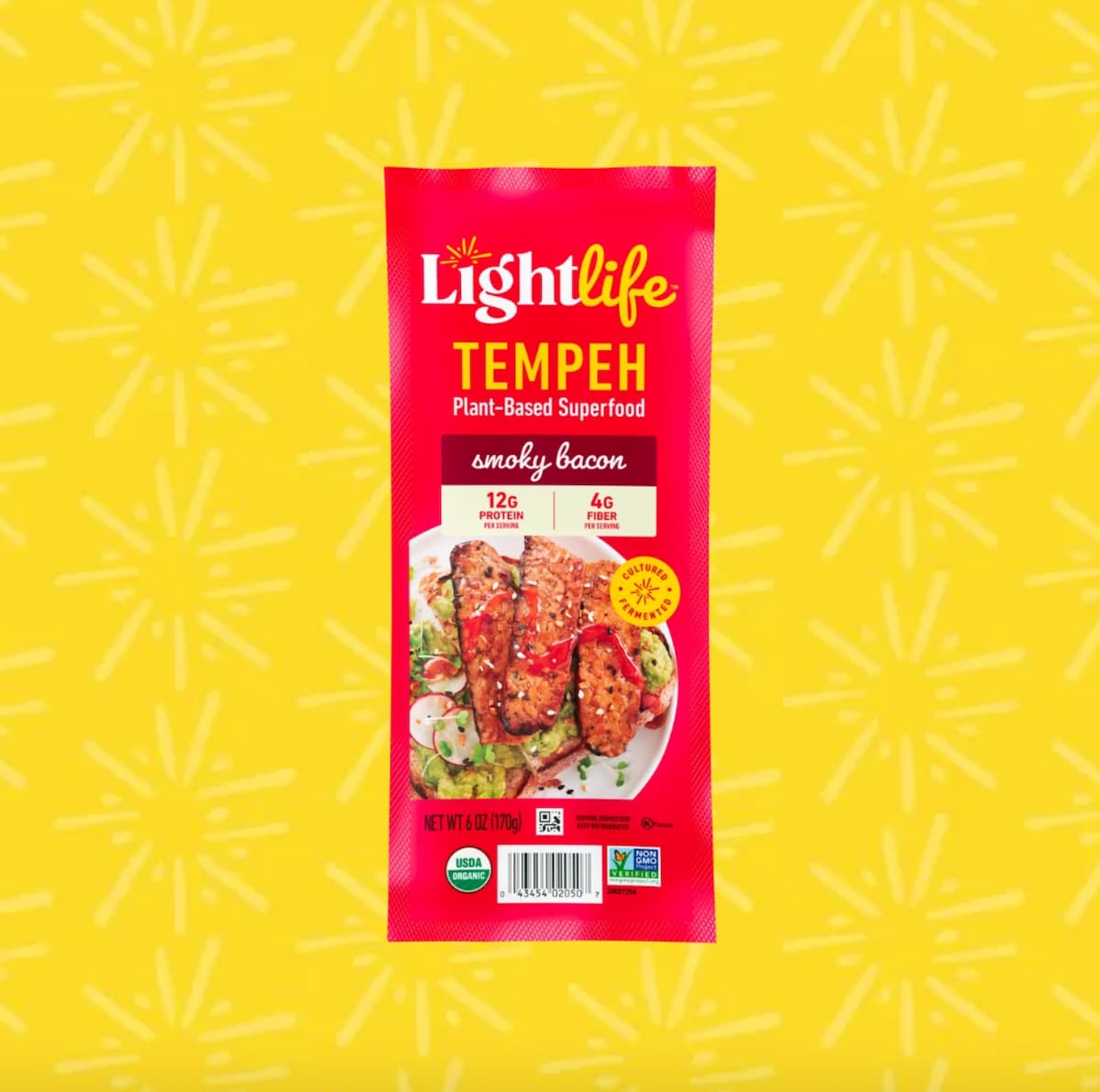 A red package of Lightlife Tempeh vegan bacon against a yellow decorative background.