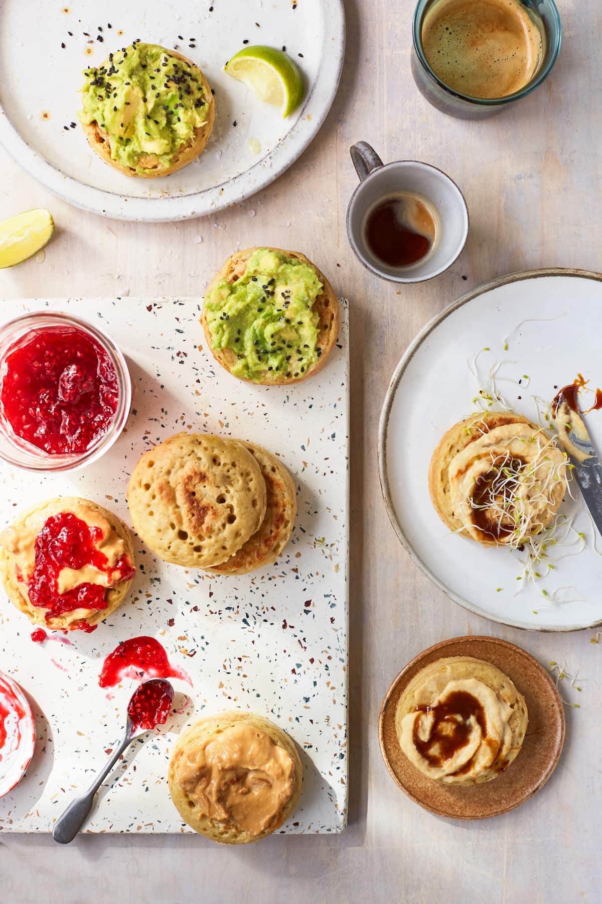 Vegan crumpets served with various toppings including mashed avocado, peanut butter and jam, and marmite with hummus.
