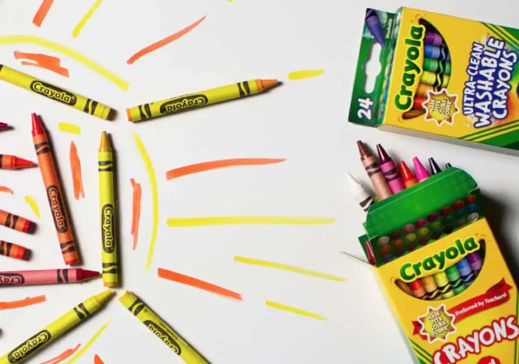 A child's drawing of a sun using Crayola crayons on white paper.