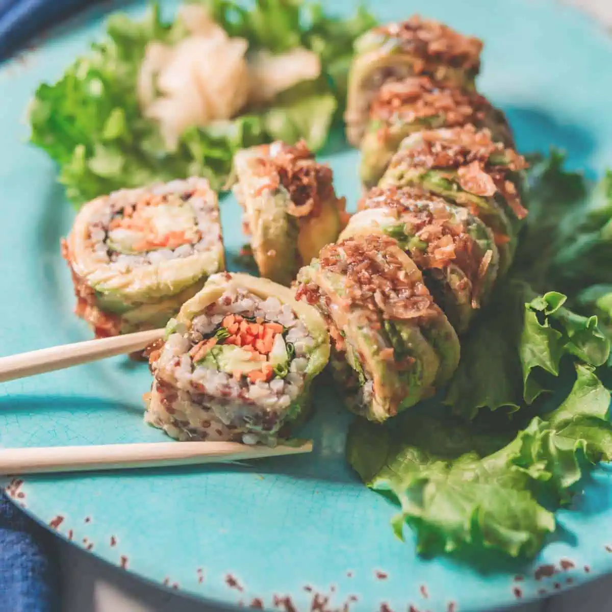 Vegan sushi on a plat with chopsticks reaching for a piece.