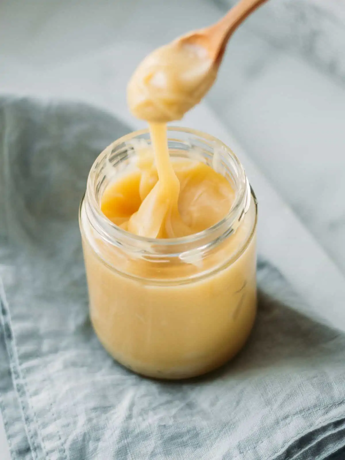vegan condensed milk in a jar with a spoon dropping some to show consistency