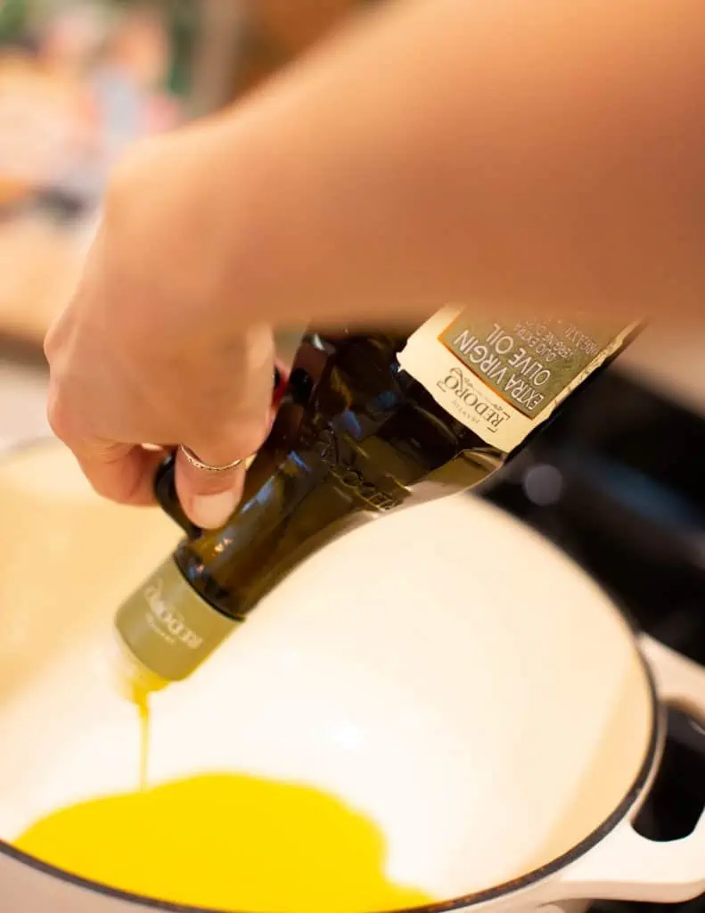 pouring olive oil into dutch oven pan