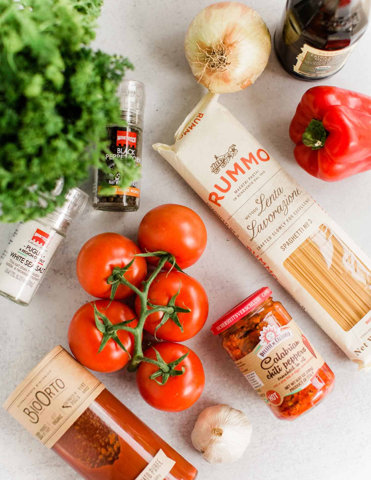 Spaghetti Arrabbiata Ingredient Flatlay with tomatoes chili peppers tomato puree pasta bell pepper garlic onion and olive oil