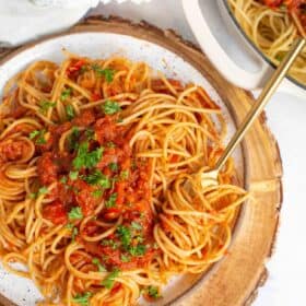 Spaghetti Arrabiata served in a rustic dish with pasta swirled on a gold fork