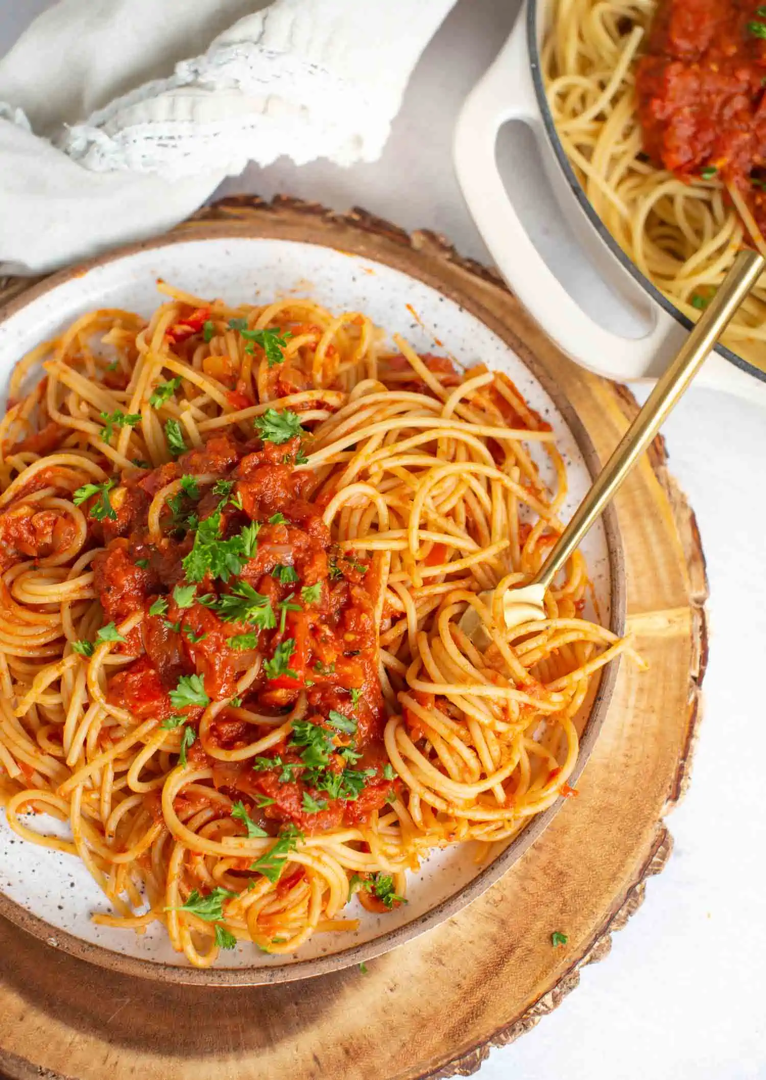 Spaghetti Arrabiata served in a rustic dish with pasta swirled on a gold fork