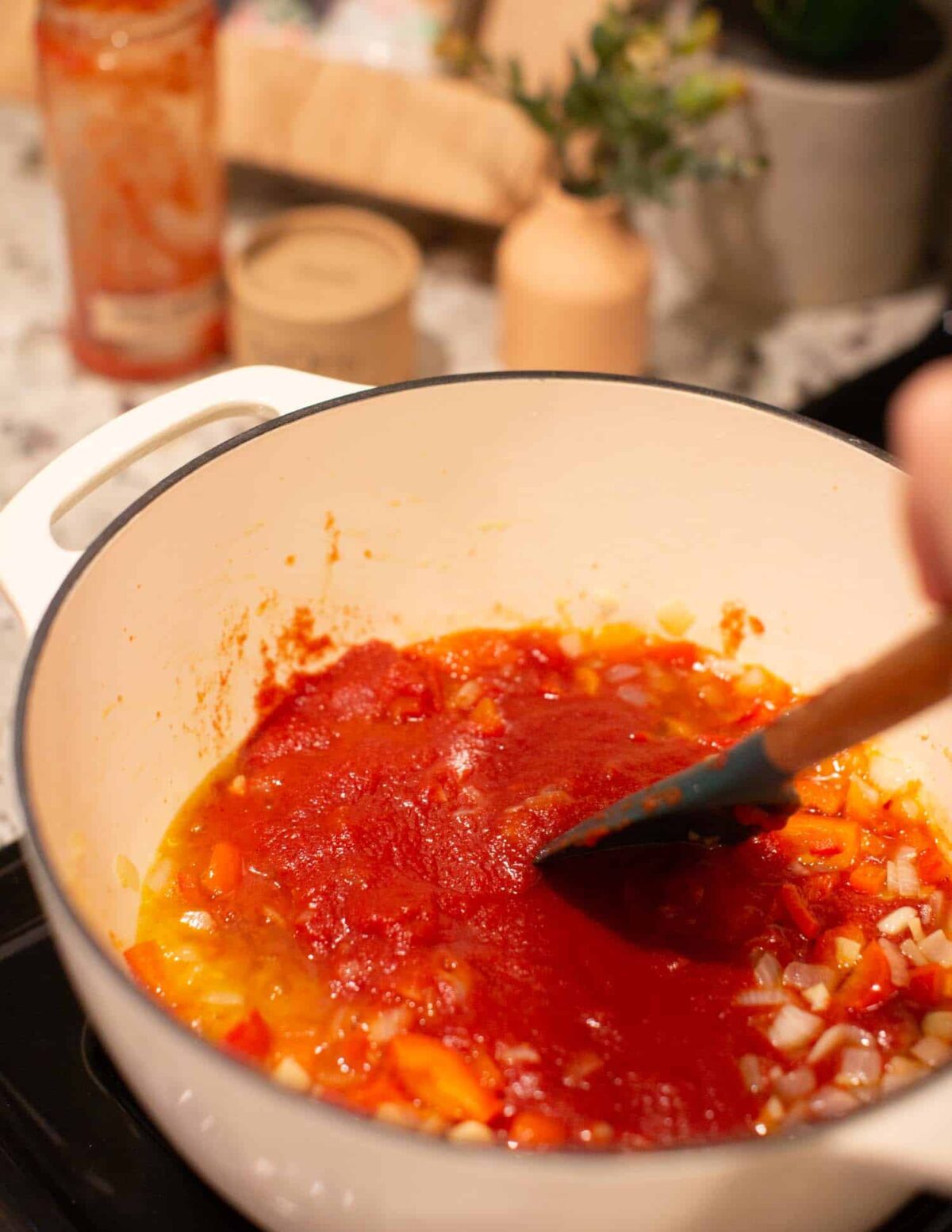 Tomatoes in sauce being added to a pot.