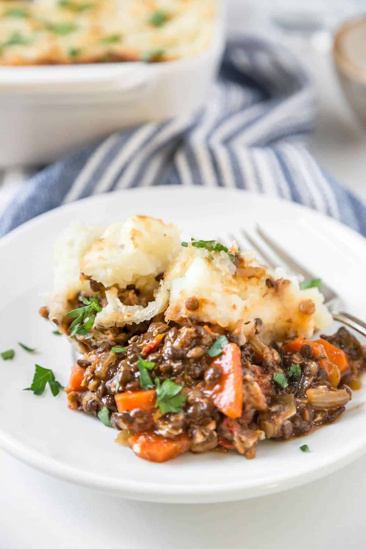 A serving of vegan shepherd's pie on a plate with a fork.