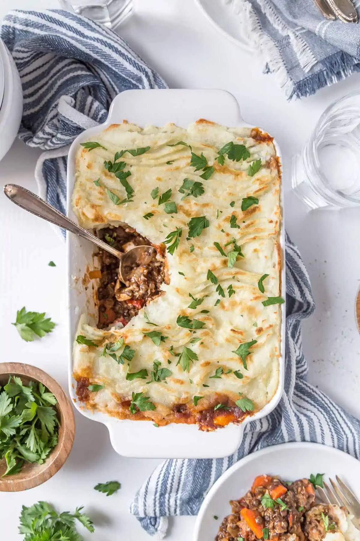 Vegan Shepherd's Pie in a casserole dish with a serving spoon and a serving missing.