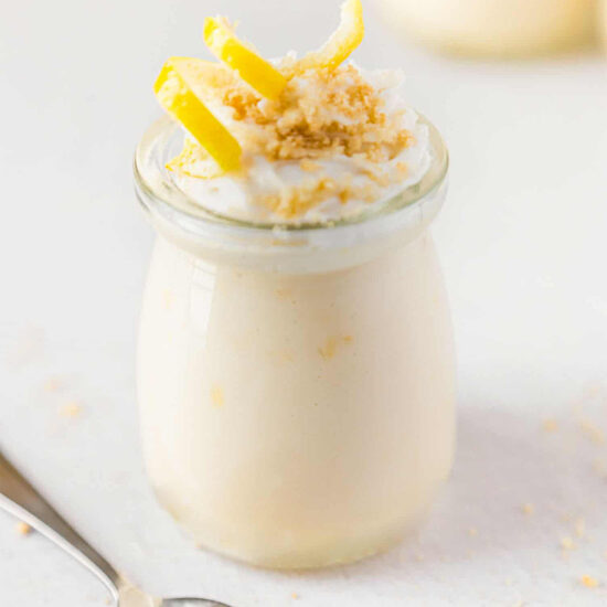 Vegan lemon custard in jar topped with vegan whipped cream and lemon zest.
