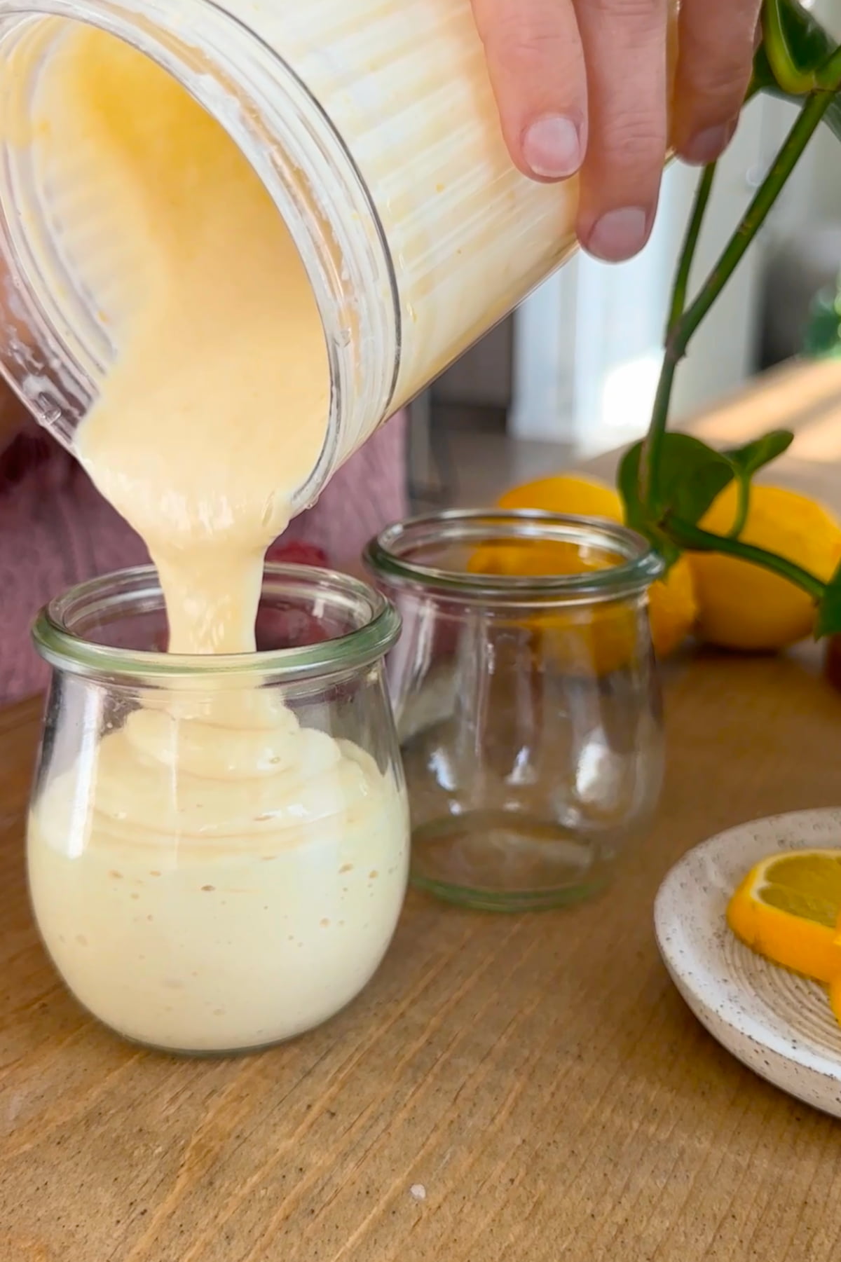 The vegan lemon custard mixture pouring from the blender cup into a glass jar.