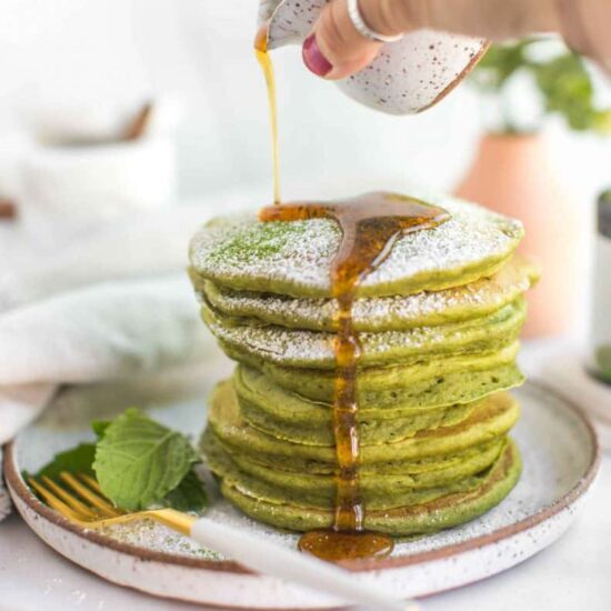 Green matcha pancakes served for breakfast with syrup.
