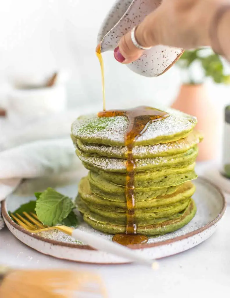 Green matcha pancakes served for breakfast with syrup.