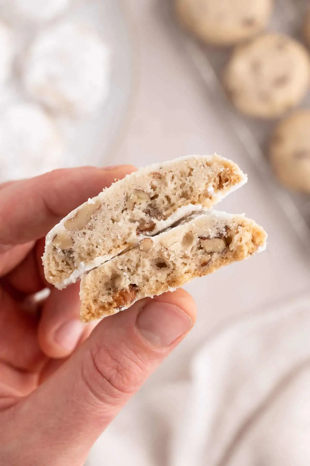 Hand holding a cookie that has been sliced in half to show the inside.