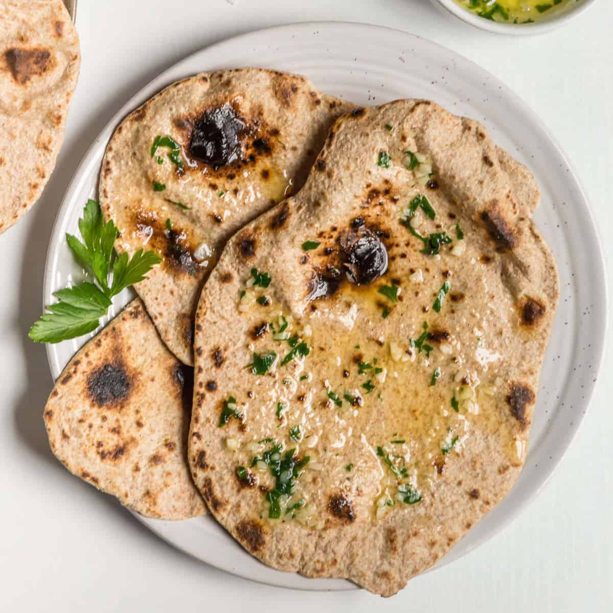 Vegan roti on a plate topped with a vegan herbed butter.