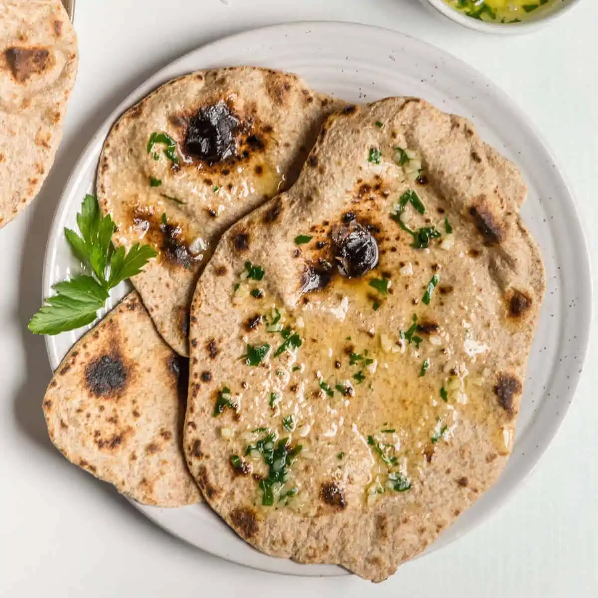 Vegan roti on a plate topped with a vegan herbed butter.