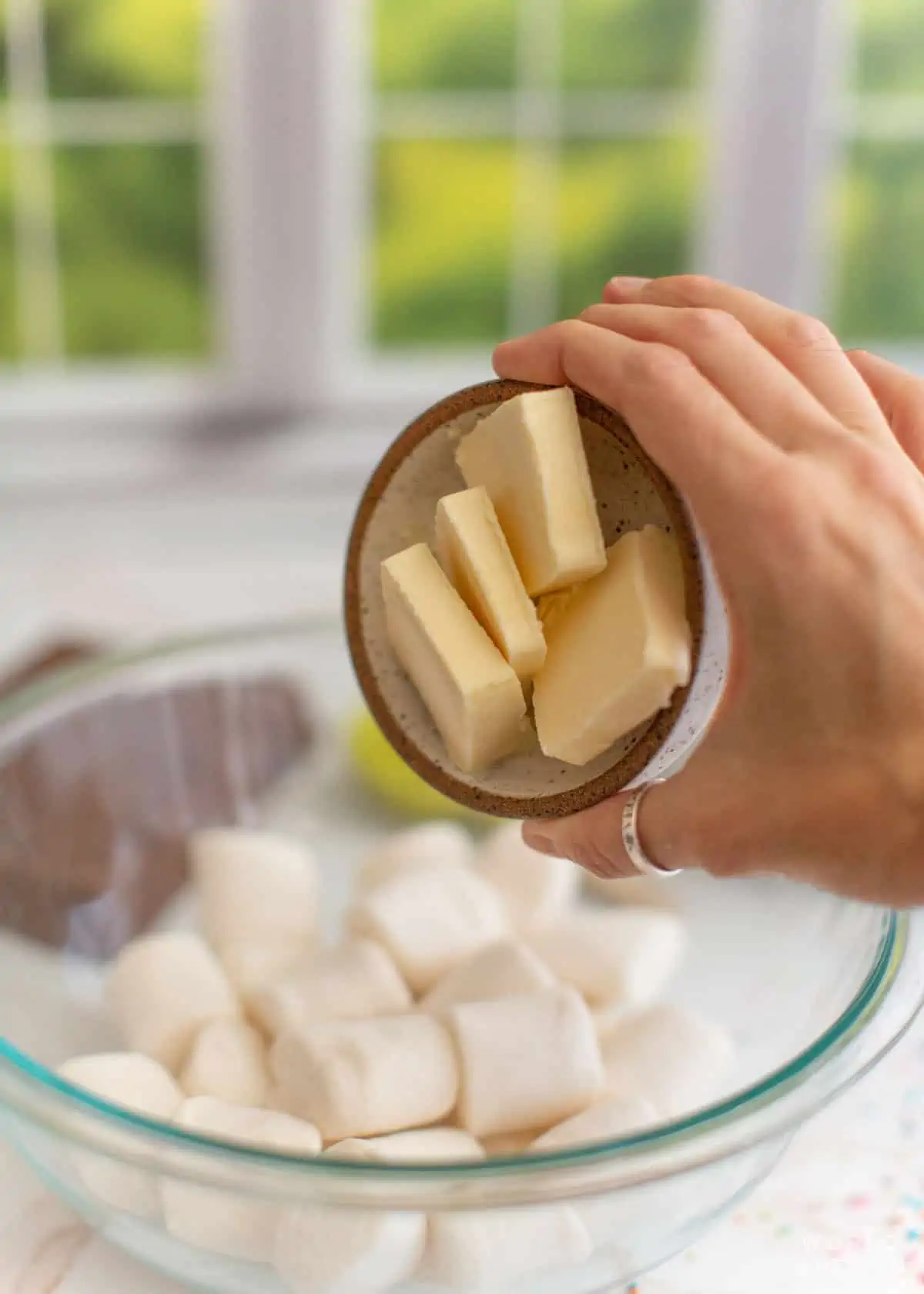 adding butter to bowl of marshmallows