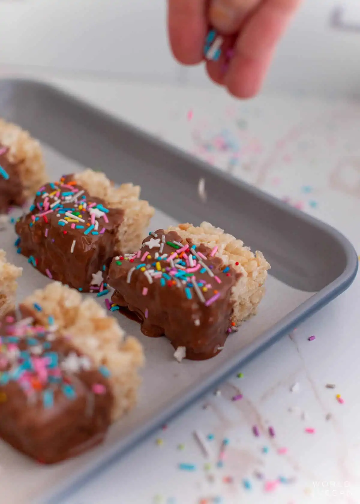 adding sprinkles to melted chocolate covered rice krispies