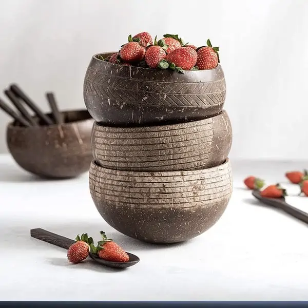 etched coconut bowls and wooden spoons stacked up with strawberries in them