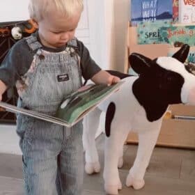 vegan kid reading a book to his stuffed animal cow