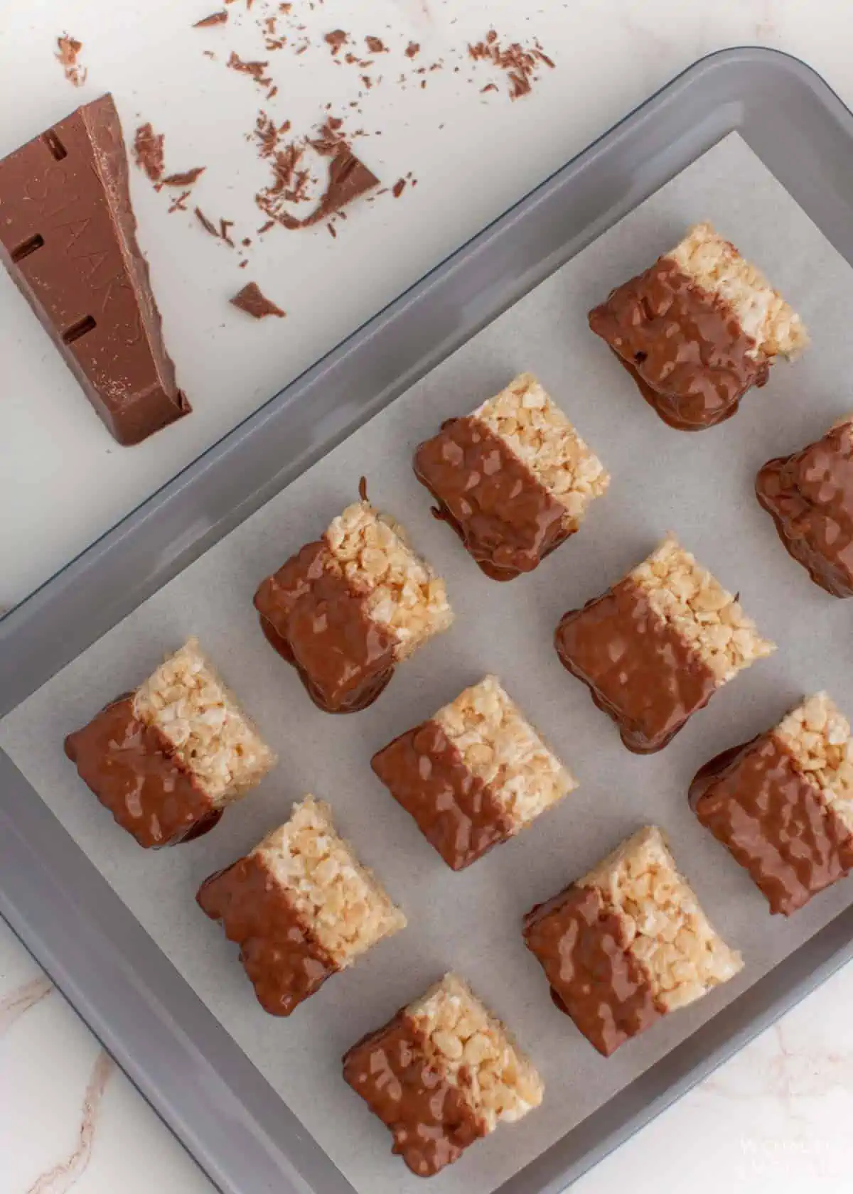 set chocolate coated rice krispies treats on baking sheet with parchment paper