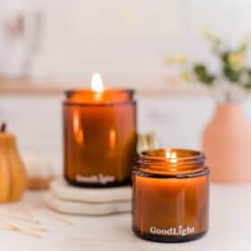 two vegan scented candles burning in glass jars