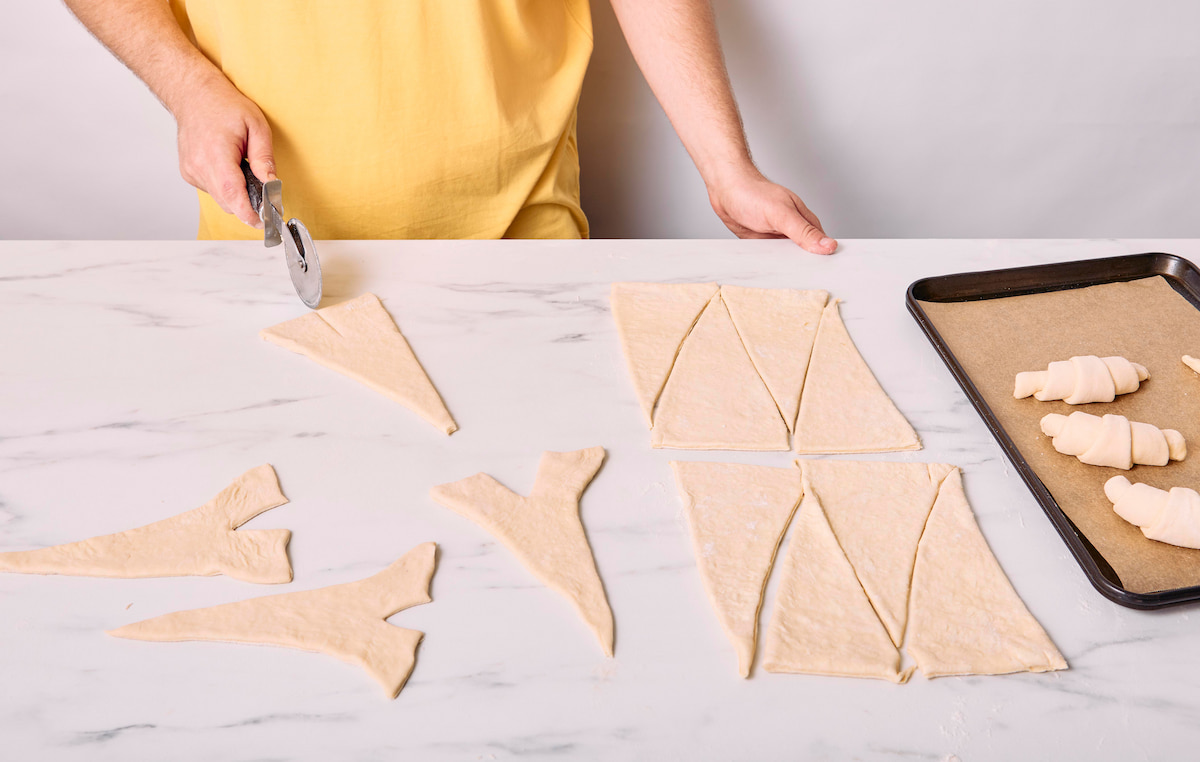 A pizza roller slicing the base of the triangle upward an inch.