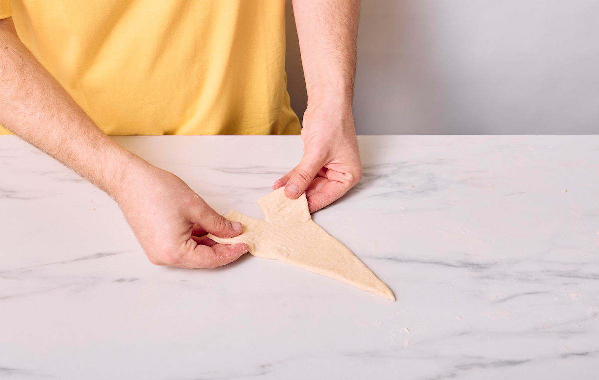 Hands gently pulling at the slice created at the bottom of the triangle to look like a mini Eiffel Tower.