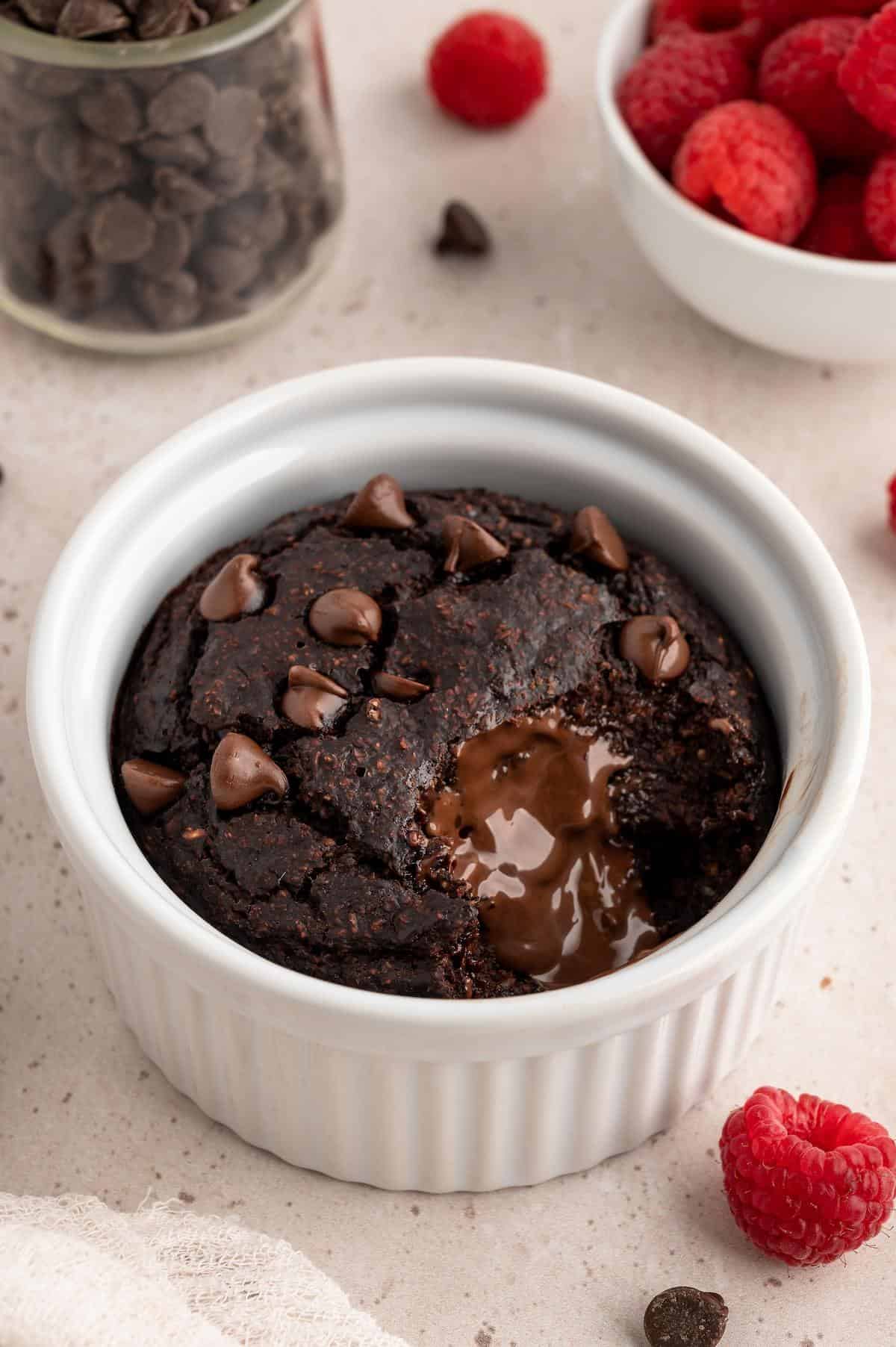 Chocolate baked oats protein mug cake with a bite missing and melted chocolate revealed.
