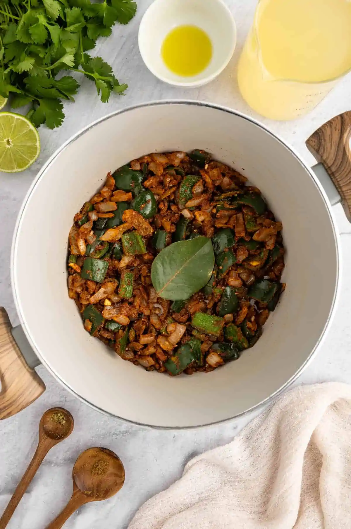 Vegan pozole in a white bowl in the prep stage with a bay leaf on top.