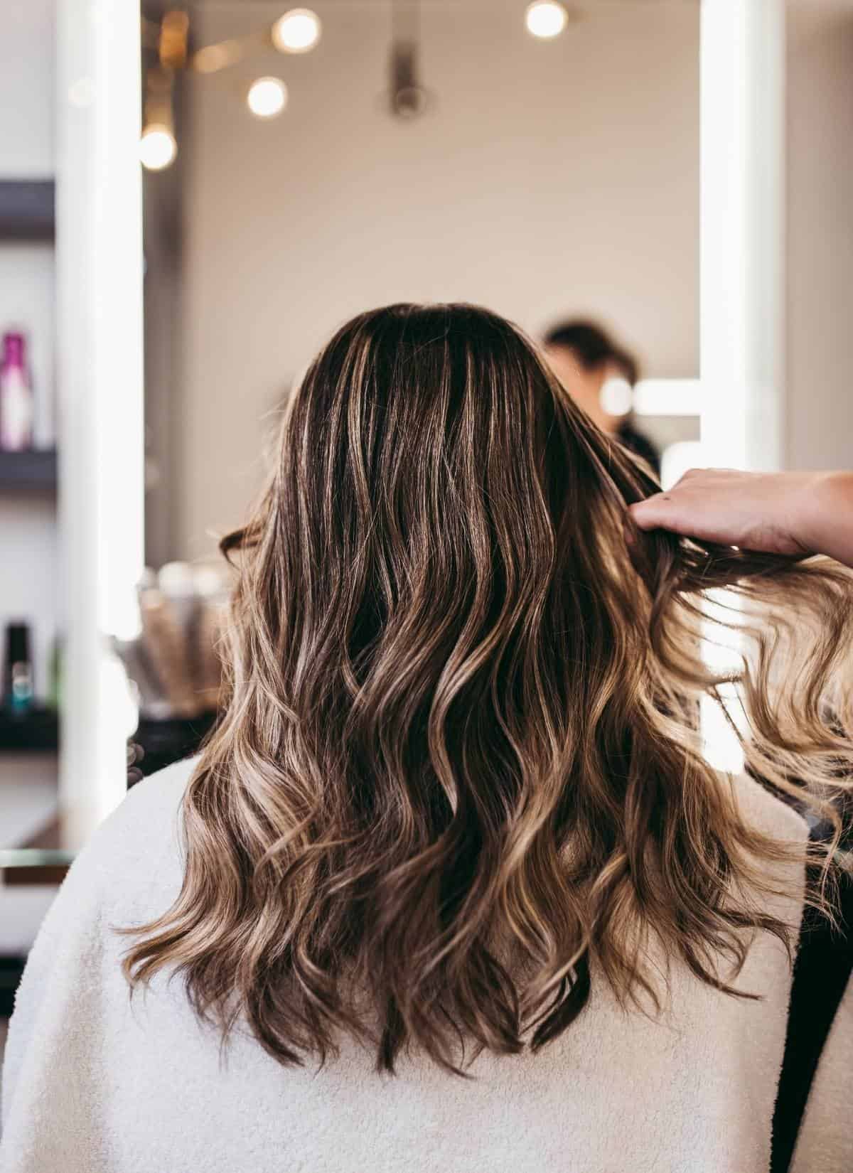 Woman with brown wavy hair getting vegan haircut